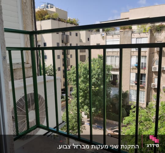 מעקה ירוק במרפסת עם נוף לבניינים